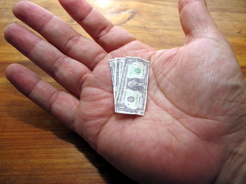 Open hand holding tiny folded US dollar bills